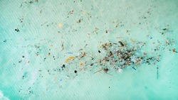 Aerial View Of Ocean Pollution, Depicting A Swath Of Colorful Plastic Debris Contaminating Turquoise Sea Waters, Highlighting Environmental Concerns