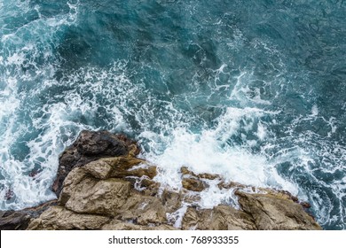 Aerial view of ocean wave crashing on rocky cliff with white spray and foam on deep blue sea water after storm. - Powered by Shutterstock