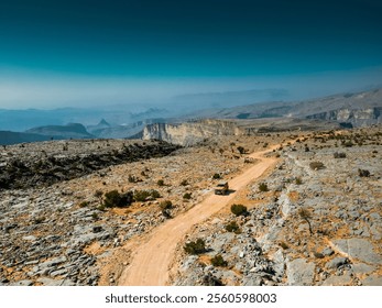 Aerial view of off-road paths in Jebel Akhdar, Oman, with a car navigating through the rugged terrain, showcasing the challenging and adventurous tracks winding through the dramatic mountain landscape - Powered by Shutterstock