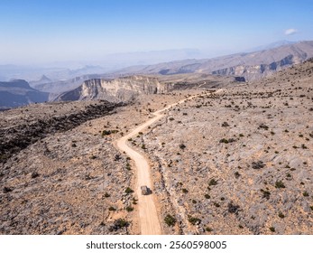 Aerial view of off-road paths in Jebel Akhdar, Oman, with a car navigating through the rugged terrain, showcasing the challenging and adventurous tracks winding through the dramatic mountain landscape - Powered by Shutterstock