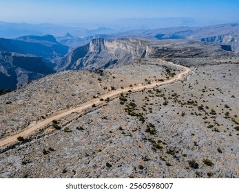 Aerial view of off-road paths in Jebel Akhdar, Oman, with a car navigating through the rugged terrain, showcasing the challenging and adventurous tracks winding through the dramatic mountain landscape - Powered by Shutterstock