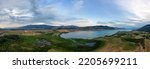 Aerial View of Okanagan Lake with farm lands and mountain landscape. Cloudy Sunset Sky. Near Vernon, British Columbia, Canada. Nature Panorama Background