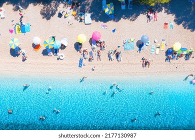 Aerial view on beach, pepole and umbrellas. Vacation and adventure. Beach and blue water. Top view from drone at beach and azure sea. View on the coast from drone.  - Powered by Shutterstock