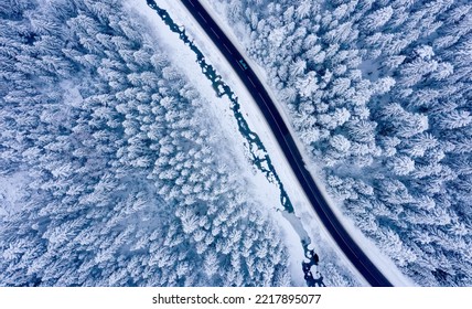 Aerial View On A Car Driving On Winter Country Road In Snowy Forest