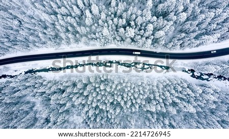 Aerial view on a car driving on winter country road in snowy forest