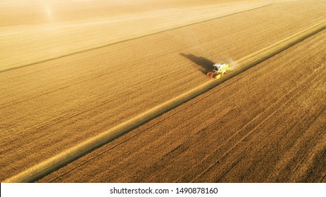 Aerial view on combine harvester gathers the wheat at sunset. Harvesting grain field, crop season. View on harvester in the partly harvested field, diagonal composition.Summer, Europe