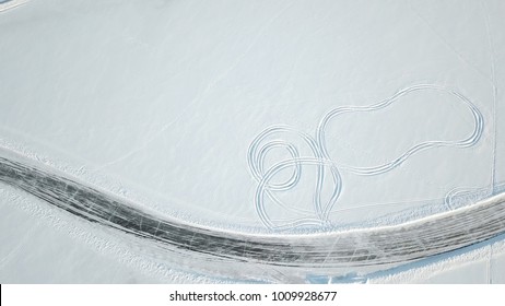 Aerial View On Driving Car At Snowy Track. One Car Driving Through The Winter Forest On Country Road. Top View From Drone