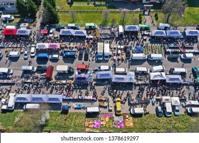 Aerial view on flea market with miscellaneous items and crowds of buyers and seller's makeshift stands.
