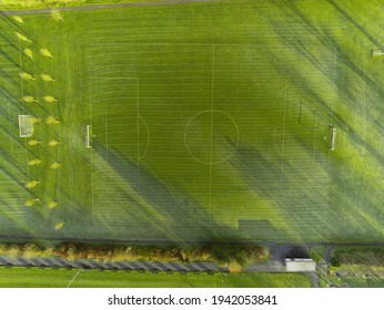 Aerial View On A Green Grass Football Or Soccer Field . Long Shadows On The Ground. Nobody. Training Pitch. Day Time