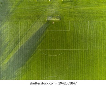 Aerial View On A Green Grass Football Or Soccer Field . Long Shadows On The Ground. Nobody. Training Pitch. Day Time