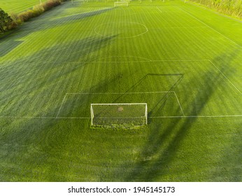 Aerial View On A Green Grass Football Or Soccer Field . Long Shadows On The Ground. Nobody. Training Pitch. Day Time