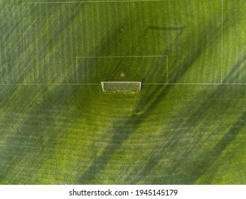 Aerial View On A Green Grass Football Or Soccer Field . Long Shadows On The Ground. Nobody. Training Pitch. Day Time