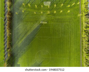 Aerial View On A Green Grass Football Or Soccer Field . Long Shadows On The Ground. Nobody. Training Pitch. Day Time