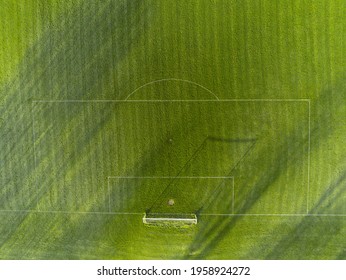 Aerial View On A Green Grass Football Or Soccer Field . Long Shadows On The Ground. Nobody. Training Pitch. Day Time