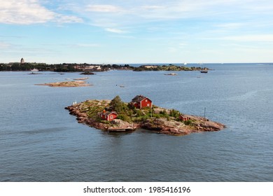 Aerial view on little islands with tiny red houses in Scandinavian style among the vast water ocean or sea, under blue sky. Outdoors, copy space.