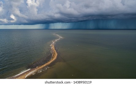 Aerial View On The Narrow Diagonal Bending Sand Spit In The Blue Hued Sea Gulf With The Approaching Thunder And Rain Cloud Front In The Uudepanga Bay, Vilsandi National Park, Estonia