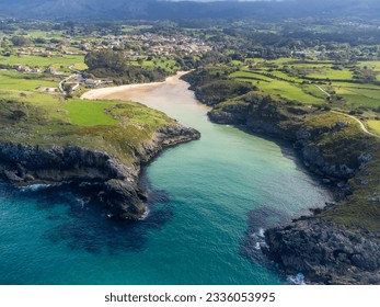 Aerial view on Playa de Poo during low tide near Llanes, Green coast of Asturias, North Spain with white sandy beaches, cliffs, hidden caves, green fields and mountains.