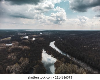 Aerial View On River Delta In Bare Trees Forest With Epic Cloudy Sky. Nature Landscape From Drone. Color Graded