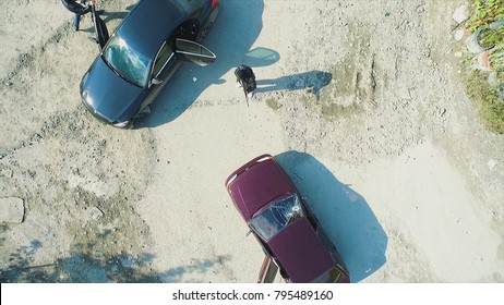 Aerial View On Robbers With Guns Shot The Car And Leave. Footage. Terrorist Or Car Thief Pointing A Gun At The Driver. An Armed Man In The Mask Threatening Pistol To The Driver Of The Car