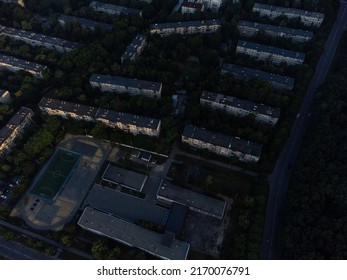 Aerial view on school buildings in residential district near green forest. Fly above streets in morning city. Treetop view on Kharkiv, Ukraine