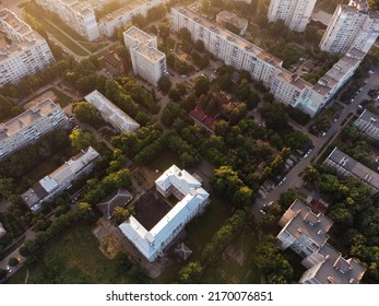 Aerial view on school buildings in green summer residential district in sun light. Fly above streets in morning city. Treetop view on Kharkiv, Ukraine