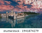 Aerial view on Sirmione Castle, Lake Garda, Italy. Medieval castle at sunset, pink clouds. An unusual castle of the 13th century, surrounded on three sides by water, with a high tower.