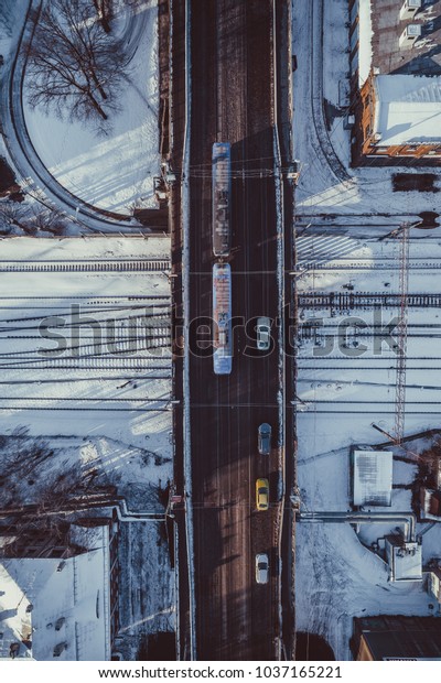 Aerial view on snowy city, car traffic, bridge\
over railways, cars driving in\
city