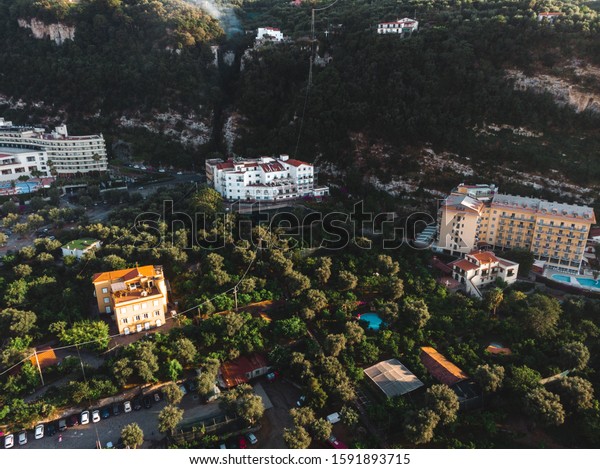 Aerial view on the Sorrento city streets, sunset,\
houses and Hotels, mountains and buildings in the distance. Travel\
and vacation concept on Italy. Infrastructure, cars and parking\
place