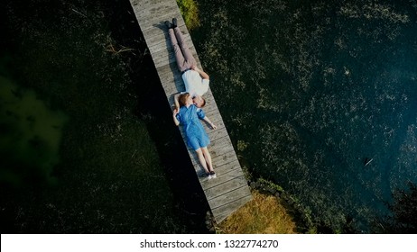 Aerial view on top. Two lovers of young people lie on a wooden b