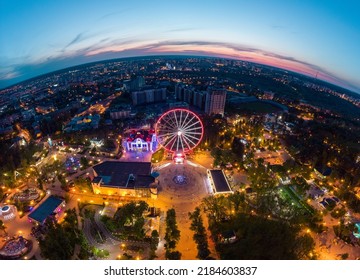 Aerial View On Vivid Evening Cityscape, Ferris Wheel And Entertainments Fish Eye Panorama. Kharkiv City Center In Sunset Colors, Amusement Gorky Central Park, Ukraine