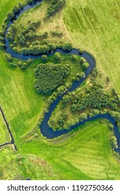 Aerial view on winding river in green field. River turns on rural landscape shot from above