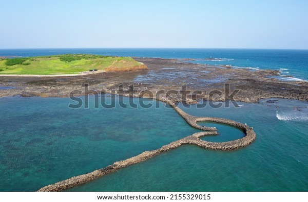 Aerial view of the One-Heart Stacked Stones\
(Tiger\'s Eye Fish Trap) bathed in the turquoise sea water, which is\
a traditional fishing weir and a popular tourist attraction, in\
Xiyu, Penghu, Taiwan