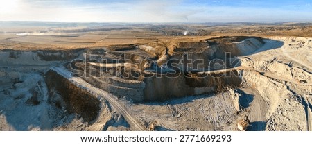 Aerial view of open pit mine of sandstone materials for construction industry with excavators and dump trucks. Heavy equipment in mining and production of useful minerals concept