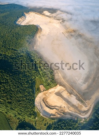 Aerial view of open pit mining site of limestone materials extraction for construction industry with excavators and dump trucks.