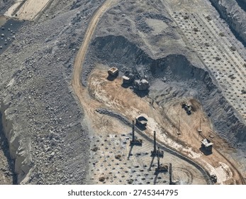 Aerial view of an open-pit mine in the process of mineral extraction next to a drilling and blasting work face with heavy machinery