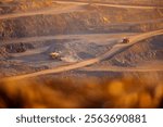 Aerial View of Open-Pit Mining Operation with Haul Trucks in a Quarry at Sunset.