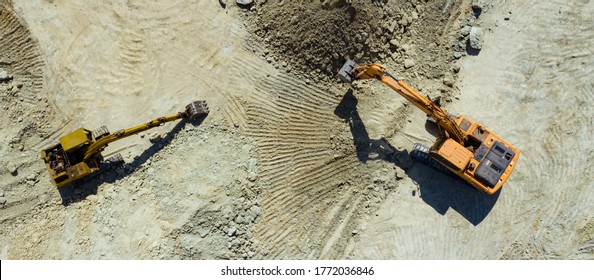 Aerial view, orange excavator working in quarries site. Activity in field construction business. Heavy equipment for digging in the ground. Top view from drone.