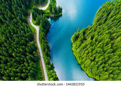 Aerial view over beautiful turquoise mountain lake and green forest. Spring in the mountains. Green forest, mountain lake. Green pine and fir trees forest and a lake. Beautiful mountain road. - Image