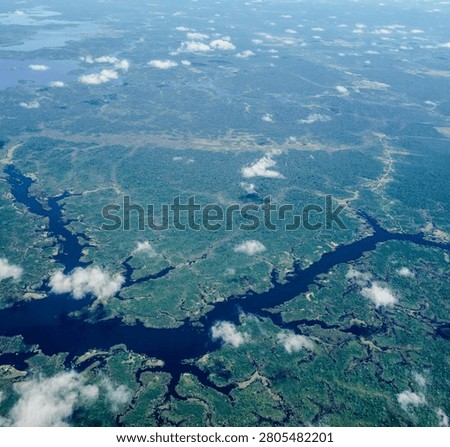 Aerial view over immense Amazon rainforest with a dark river cutting through forest. Amazonas, Brazil.