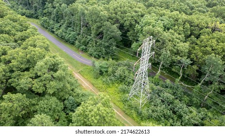 An Aerial View Over A Large Tower And Electrical Power Lines In The Midst Of Tall Green Trees On A Sunny Morning On Long Island, NY.