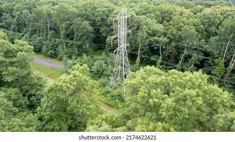 An Aerial View Over A Large Tower And Electrical Power Lines In The Midst Of Tall Green Trees On A Sunny Morning On Long Island, NY.