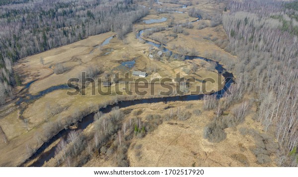 Aerial view over natural landscape\
with the native forest and bending river with semi-natural\
conservation managed floodplain meadows in Soomaa NP,\
Estonia