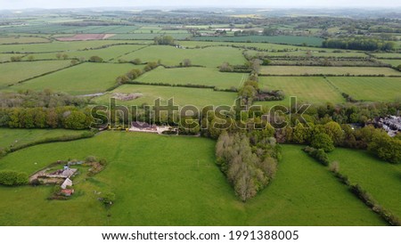 An aerial view over open countryside with hedgerows and rolling fields