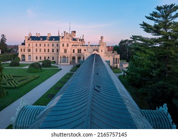 Aerial view over orangery to Lednice castle, Moravia, Czechia. A fairytale castle in a baroque garden, lit by the morning sun. UNESCO cultural heritage. Spring season, no people.