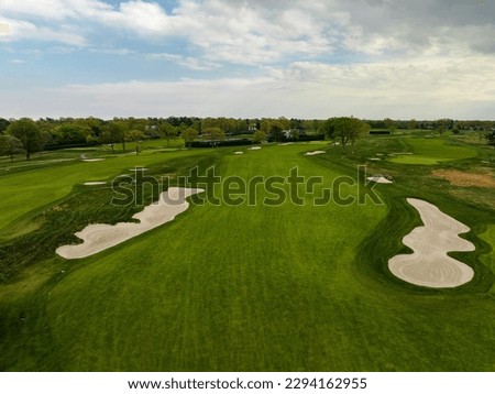 An aerial view over a pristine golf course on Long Island, New York during a beautiful day with blue skies and white clouds. No one was playing golf today.