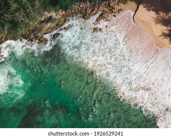 Aerial view over rocks landscape and waves splash on the beach at Naithon Beach, Phuket, Thailand