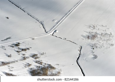 Aerial view over snowy field and small river