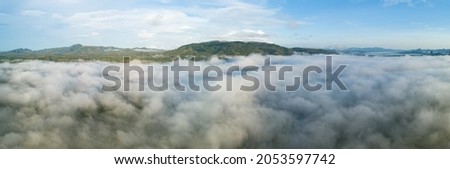 Aerial view Panorama of flowing fog waves on mountain tropical rainforest,Bird eye view image over the clouds Amazing nature background with clouds and mountain peaks in Thailand.
