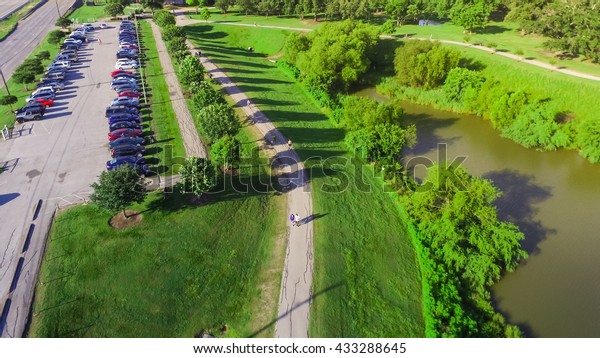 Aerial view of park entrance next to
highway in Houston, Texas, US. Also visible is a lake side walking
trail surrounded by green trees, warm morning light.Urban
recreation, healthy
lifestyle.Panorama