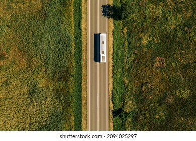Aerial view of passenger bus on road through countryside, top view from drone pov
